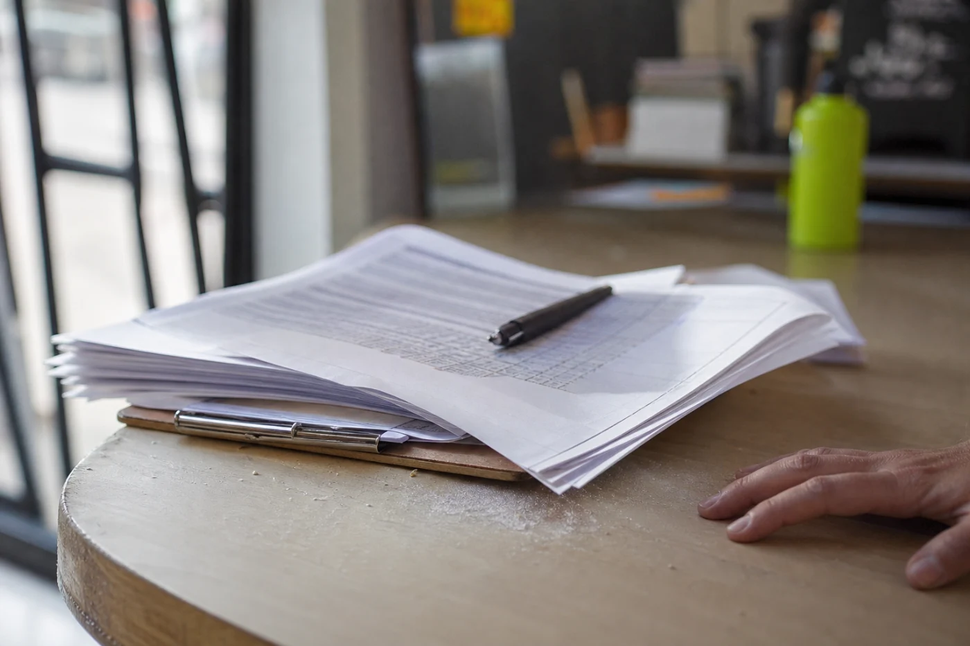A printed membership agreement fanned across a reception counter with a pen resting on it and a hand at the frame edge.
