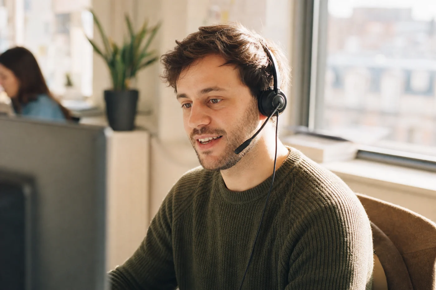 A support specialist wearing a headset at their desk, mid-conversation with a customer.